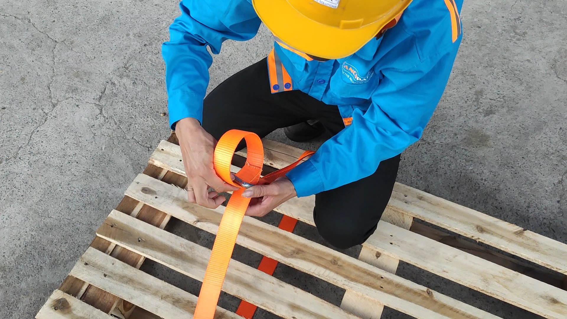 Kỹ thuật viên thao tác với dây đai chằng hàng trên pallet.